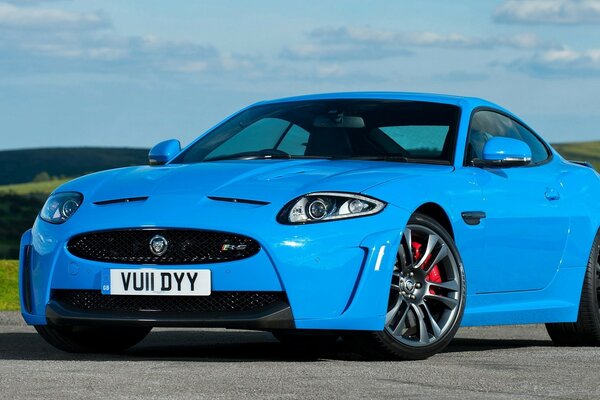 Blue jaguar on the road surrounded by mountains