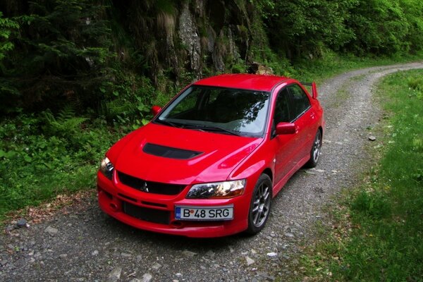 A red car is parked on a narrow road