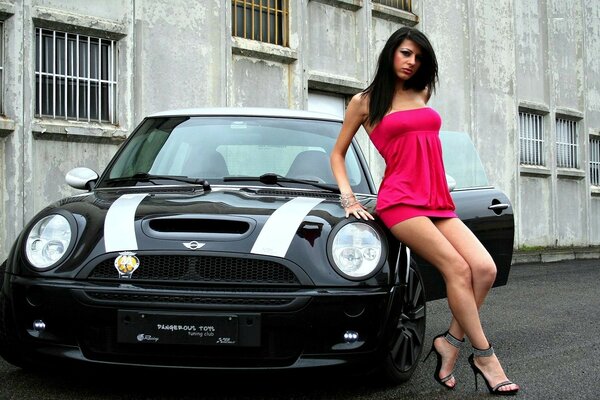 A girl in a pink dress sat down on a car