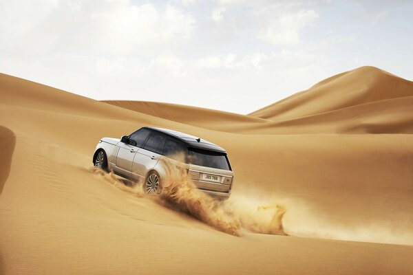 SUV che corre sulle dune gialle del deserto