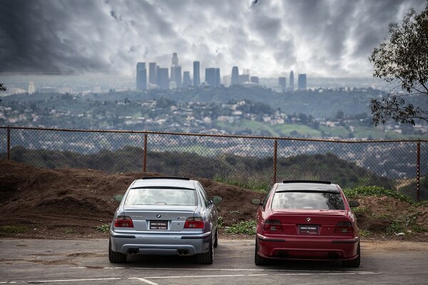 Red, and blue bmw rear behind the fence on the background of the city