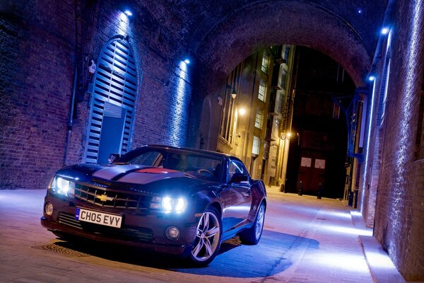 Une Chevrolet Camaro noire dans une ruelle de nuit