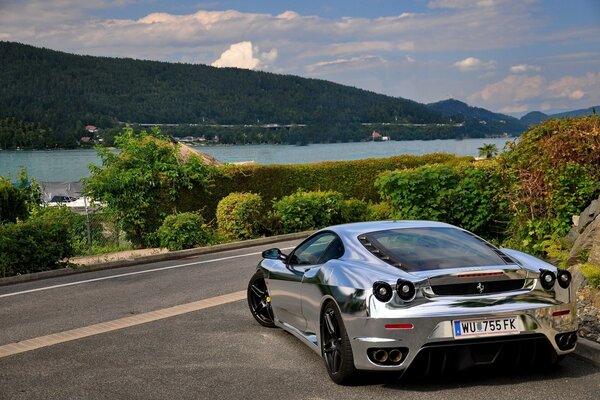 Ein spiegel -silberner Ferrari auf der Strecke vor dem Hintergrund eines malerischen Hafens