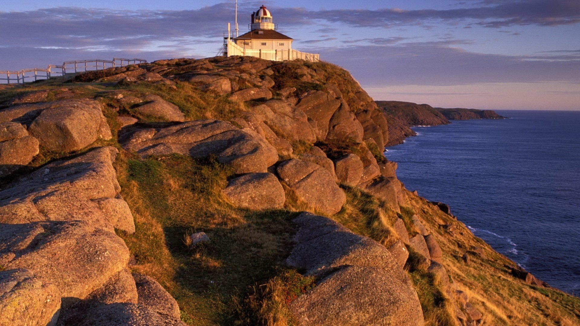 the ledge in the sea stones house by the water sea lighthouse mountains fence surf the sky sunset