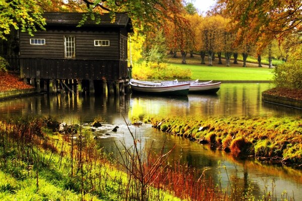 Otoño brillante con una casa junto al agua y barcos