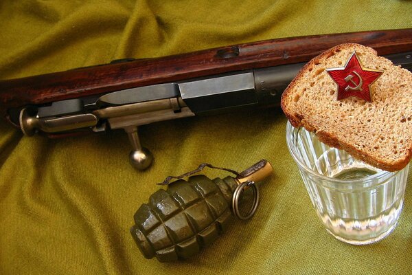 A machine gun, a grenade, a glass of vodka and bread on a cloth