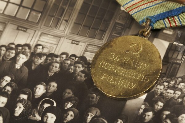 Medal za naszą sowiecką ojczyznę na tle starego zdjęcia ludzi