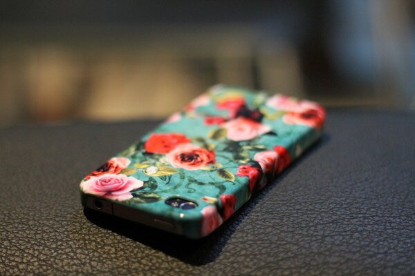 An iPhone with a beautiful case on which roses are depicted