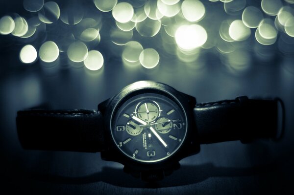 A watch with a leather strap on a background of glare