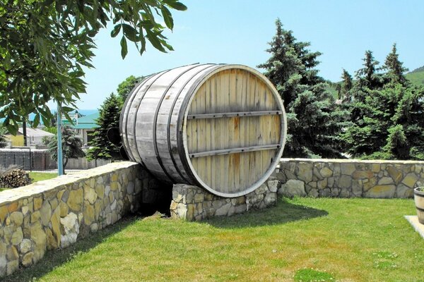 A wooden barrel among the blue sky and fir trees