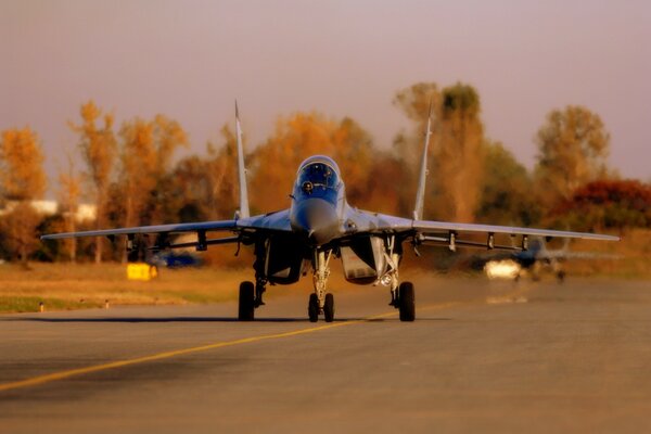 A gray fighter jet lands on the runway