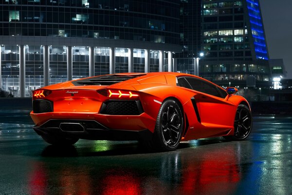 Pomarańczowy lamborghini aventador na tle nocnego miasta