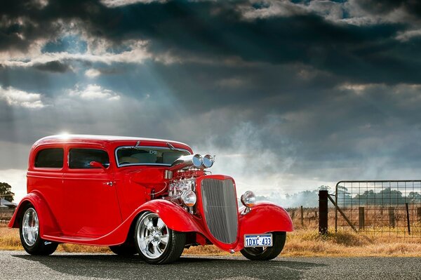 Red classic Ford on the background of a stormy sky