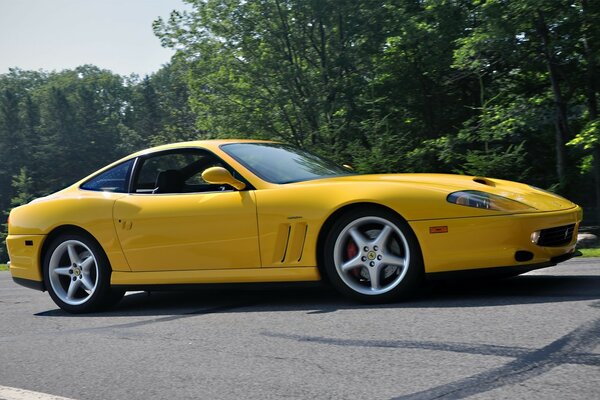 Yellow Ferrari on the road near green trees