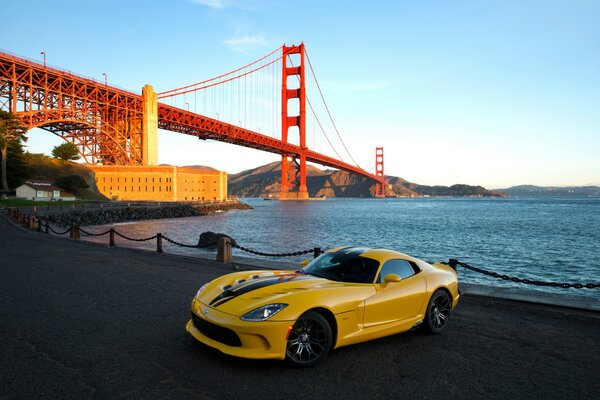 Auto am Strand mit Brücke bei Sonnenuntergang