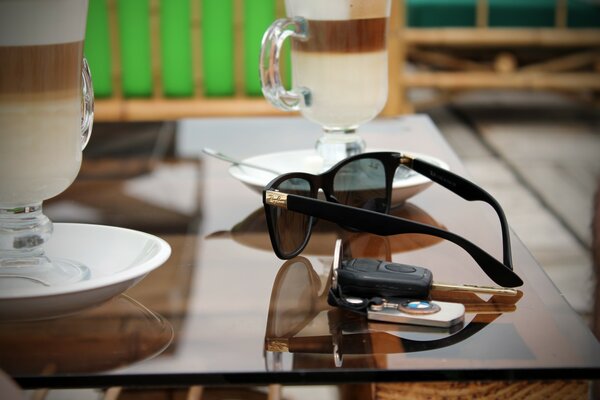 A table on which there are mugs, glasses and keys with a bmw keychain are lying