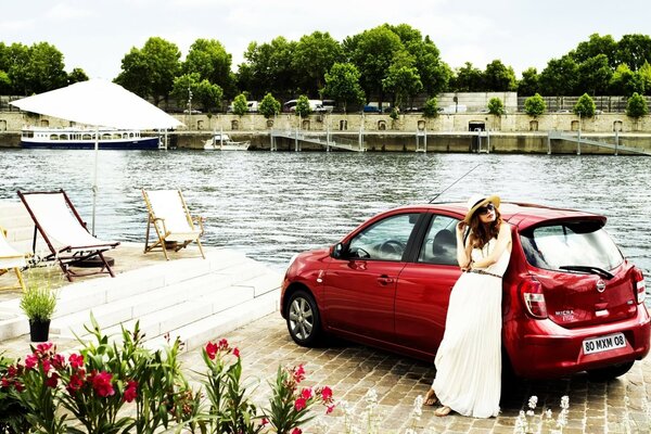 A girl and a red car near the river