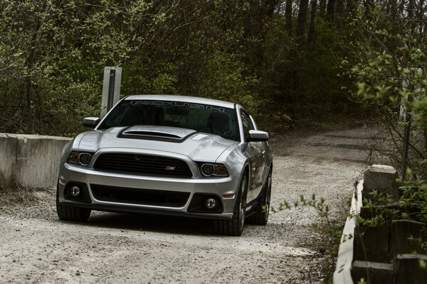 L auto mustang d argento guida lungo la strada fuori città