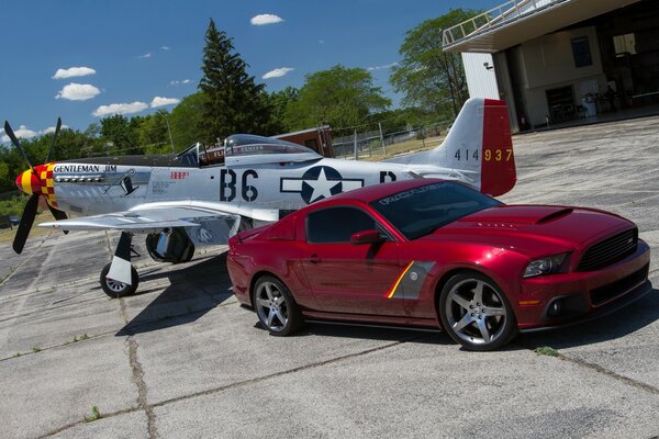 Voiture de sport rouge Ford à côté de l avion sur la route