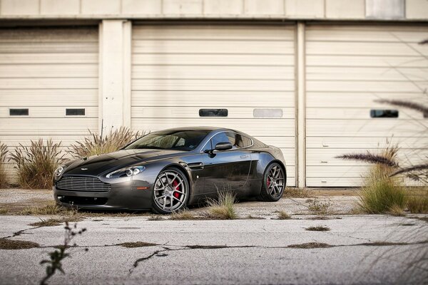 Voiture Aston Martin gris foncé sur fond de garages fermés