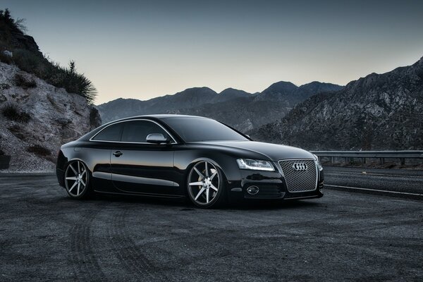 Audi negro en la carretera por la noche en las montañas