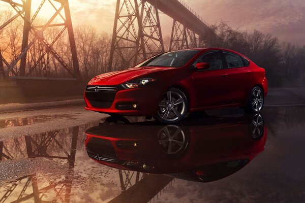 Red sports car on the road in puddles after rain