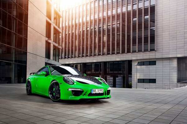 Grüner Porsche mit schwarzen Einsätzen vor dem Hintergrund eines modernen Gebäudes im Sonnenlicht