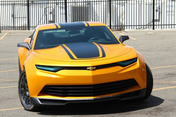 Hot sweet Chevrolet Camaro on a sunny street on a fence background