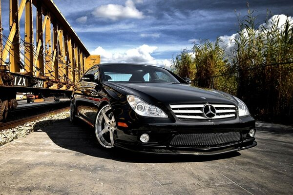 Mercedes Benz black stands in front of the railway cars