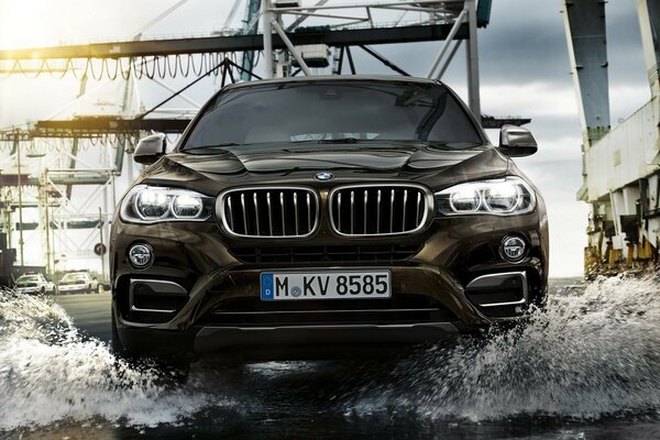 A black BMW crossover rushes through a puddle