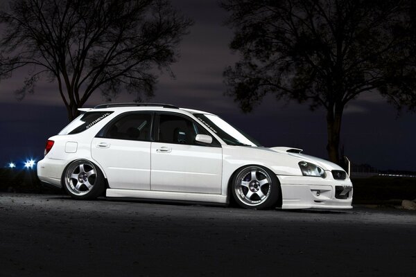 White Subaru rides through the night city