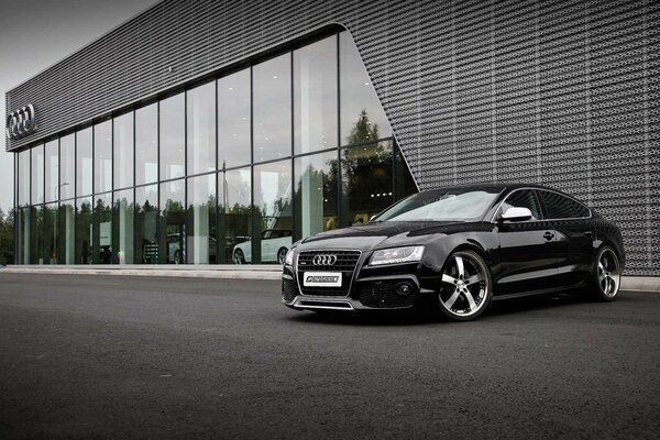 A beautiful black car is parked at the entrance to the building