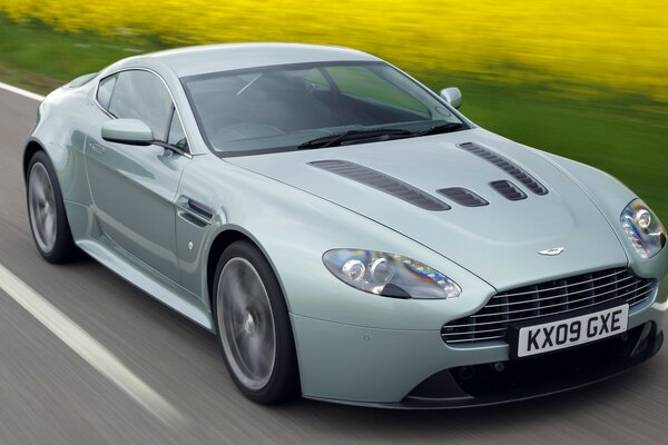 The Aston car is driving fast on the expressway