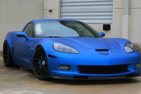 Blue corvette on the background of a white building