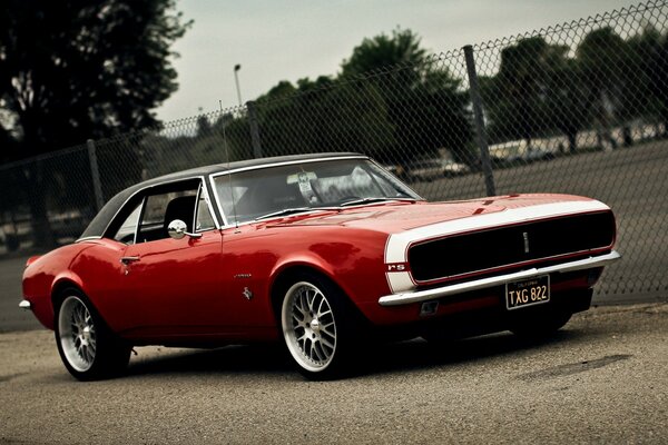 Red Camaro on the background of a sports field