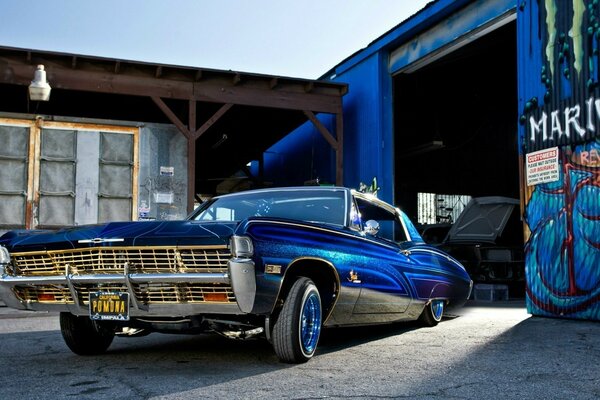 Blaues Lowrider-Auto in der Nähe der Garage