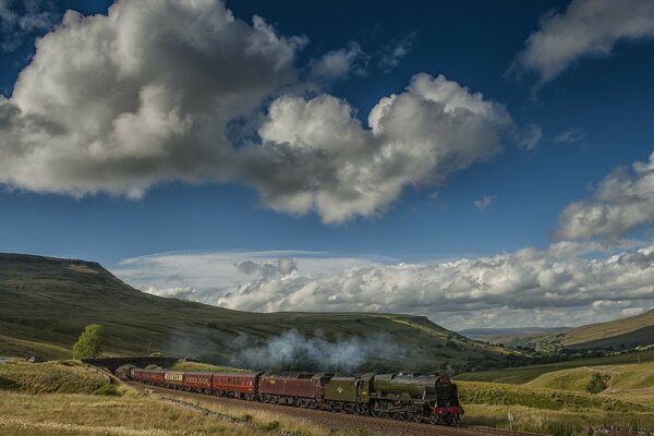 Treno con locomotiva a vapore su un bellissimo terreno con nuvole