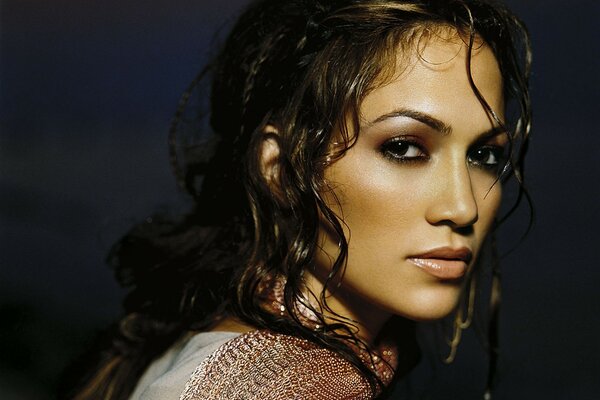 A brunette with wet curly hair and golden skin languidly looks forward