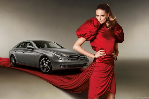 A model in a red dress on the background of a Mercedes car