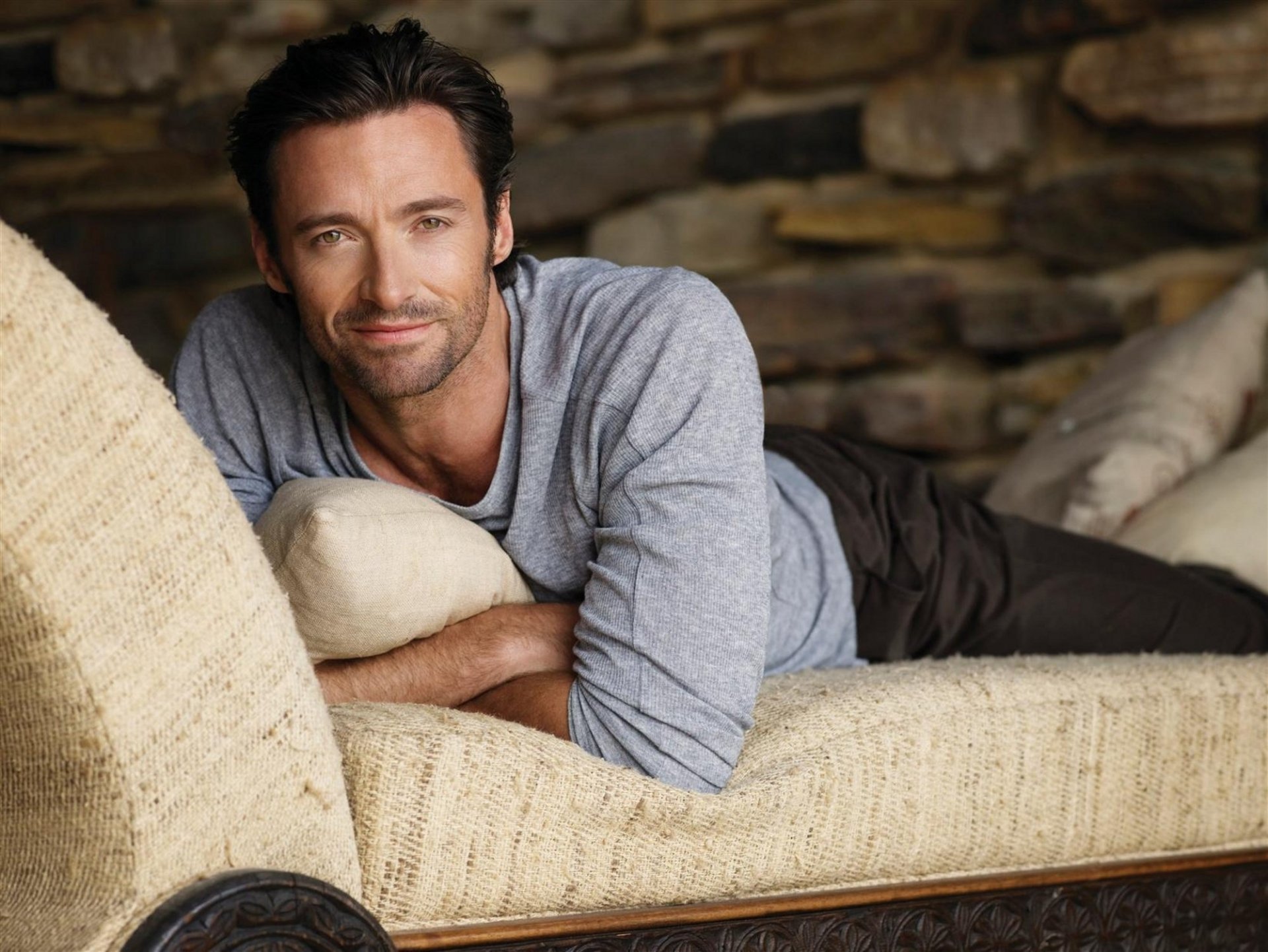 descanso en el sofá hugh jackman cerdas ligeras mirada sonrisa actor celebridad guapo sin afeitar ojos cara