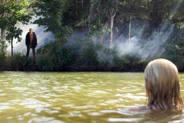 A girl in the water looks at a guy on the shore