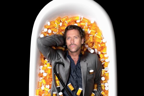 Doctor Dr. House is lying in a bathtub with pills