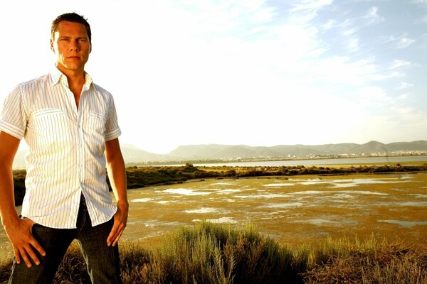 A man poses in a white shirt