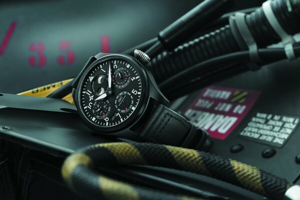 A stylish black watch lies next to the cable