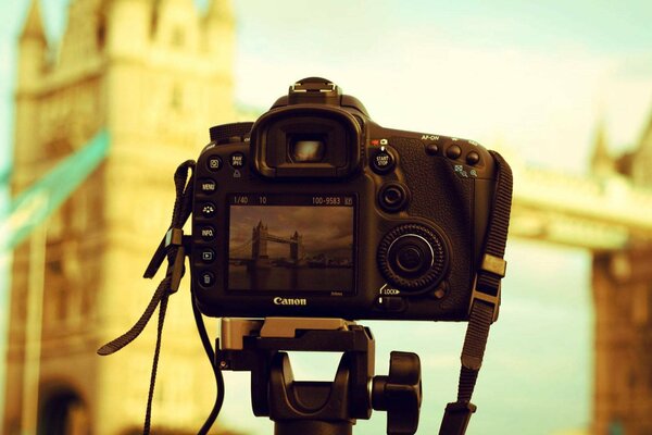 The camera is on a tripod against the background of the building