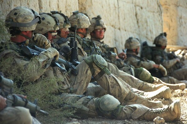 Vacationers, soldiers in uniform sitting near the wall