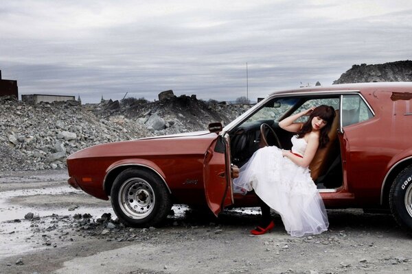 Sposa in abito bianco si siede in auto maiale