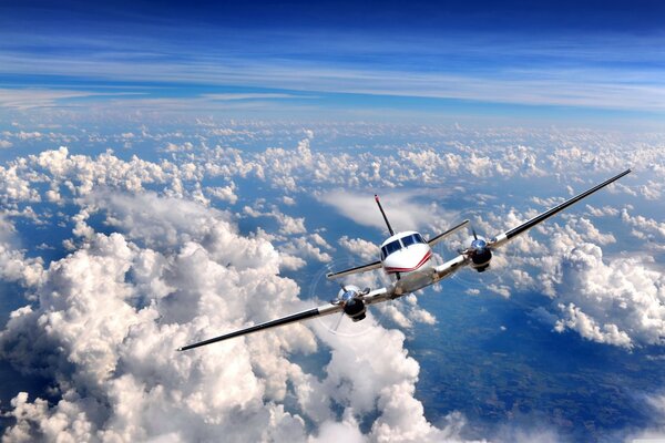 The plane is high in the clouds under a blue sky