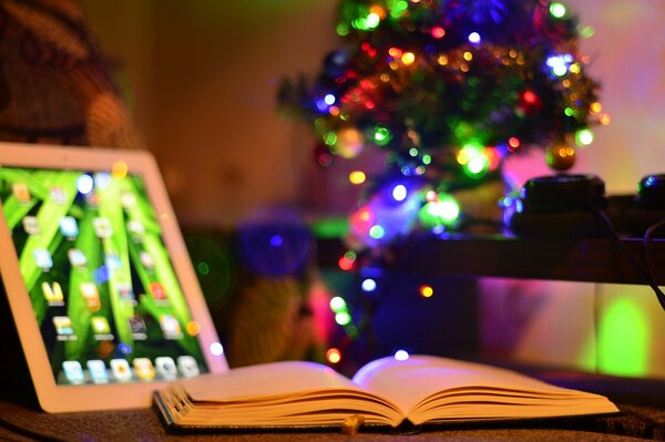 Árbol de Navidad en la habitación. Tableta y libro en la mesa