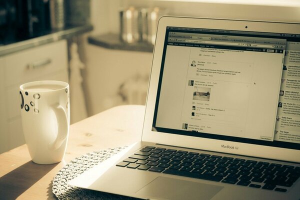 Image of a laptop on a table with a cup of coffee